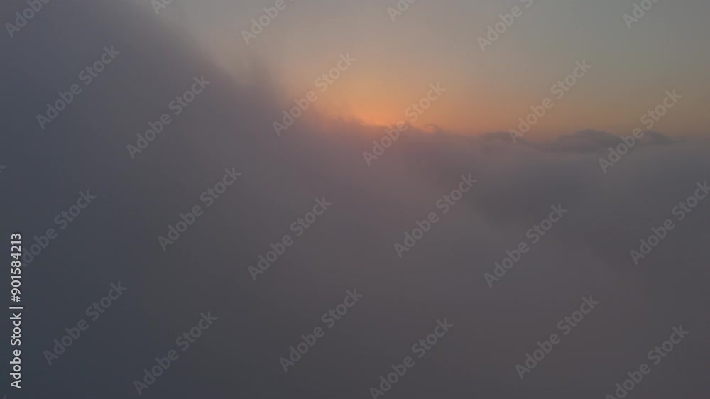 Airplane view during sunset, high above the clouds. The sun’s orange glow lights up the cloud Airplane view during sunset, high above the clouds. The sun’s orange glow lights up the cloud