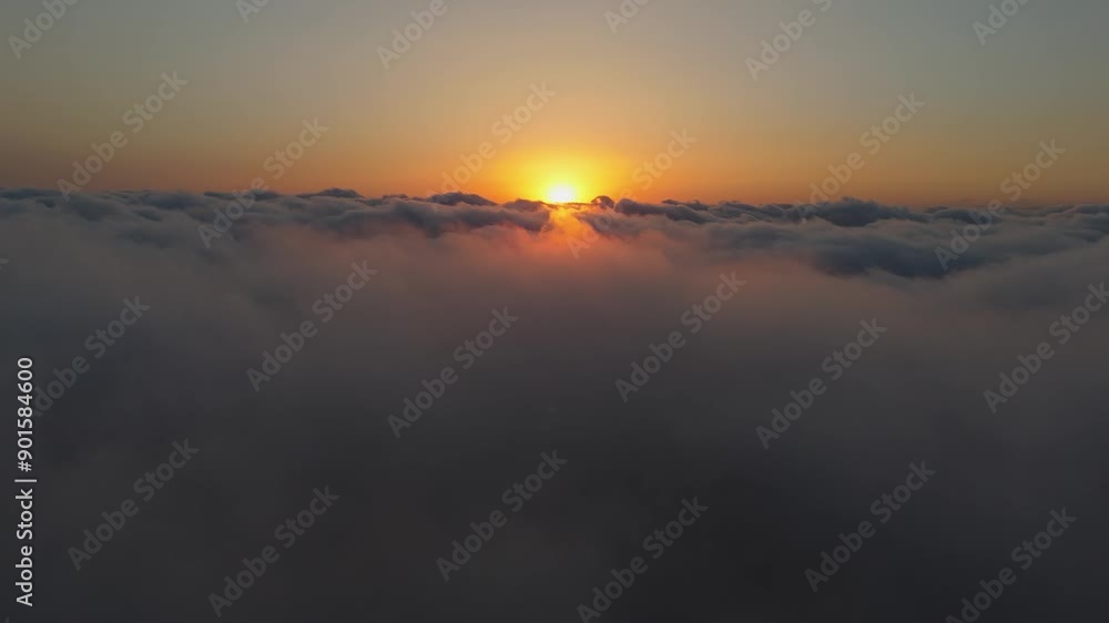 Airplane view at sunset, above a cloud expanse. The sun’s rays create an orange glow on the clouds. Flying through billowy clouds, beautiful scenes above. Airplane view at sunset, above a cloud expanse. The sun’s rays create an orange glow on the clouds. Flying through billowy clouds, beautiful scenes above.