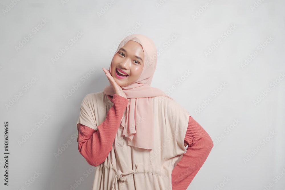 A young woman in a pink headscarf and a tan dress with a coral sleeve smiles at the camera A young woman in a pink headscarf and a tan dress with a coral sleeve smiles at the camera