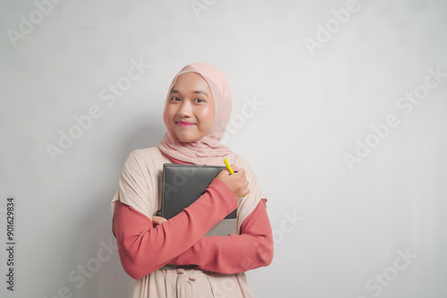 Young woman in hijab holding a notebook and pen