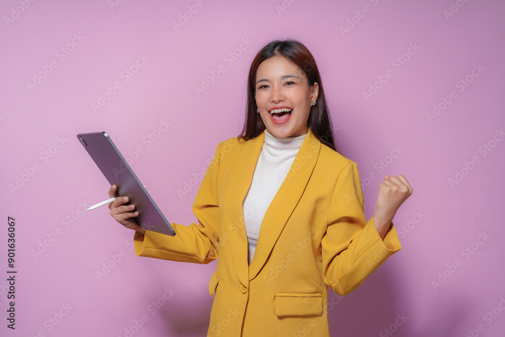 Young professional woman is holding a digital tablet and celebrating a success with excitement Young professional woman is holding a digital tablet and celebrating a success with excitement