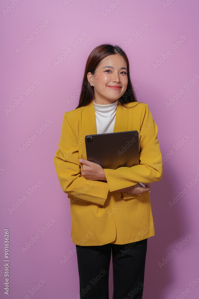 Young professional woman is holding a tablet and smiling on a purple background Young professional woman is holding a tablet and smiling on a purple background