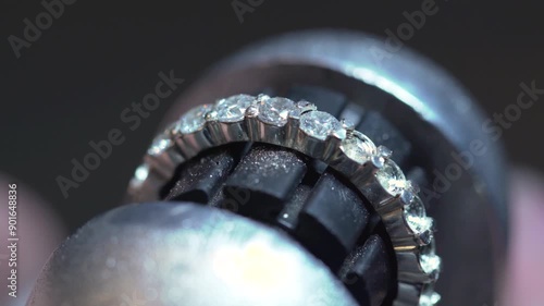 A jeweler, using a special machine, inlays a wedding ring made of gold, silver or other precious metals with diamonds in the jewelry manufacturing and processing workshop