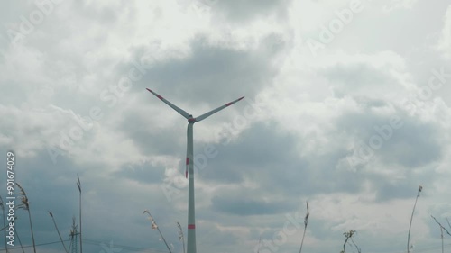 Wallpaper Mural Windmill operating and generating green electricity under cloudy sky, copy space. Wind turbine with electrical equipment and high voltage power line in the background Torontodigital.ca