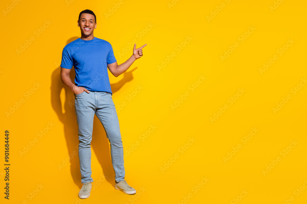 Full size photo of pretty young male point empty space wear trendy blue outfit isolated on yellow color background Full size photo of pretty young male point empty space wear trendy blue outfit isolated on yellow color background