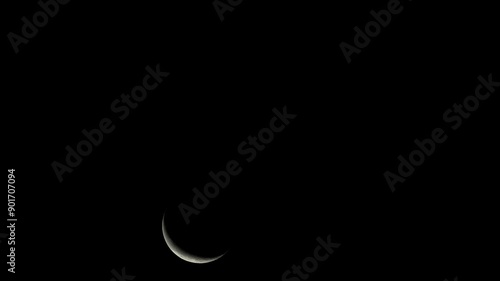 A solitary crescent moon ascends in the dark night sky, its luminous curve a beacon of tranquility. Xindian District, Taiwan. photo