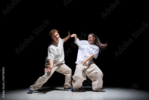 Freestyle. Imagination. Young talented man and woman in light clothes dancing hip-hop against black studio background. Concept of contemporary dance, hobby, youth, entertainment