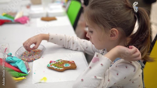 A joyful child decorates a gingerbread cookie during a colorful, fun holiday celebration