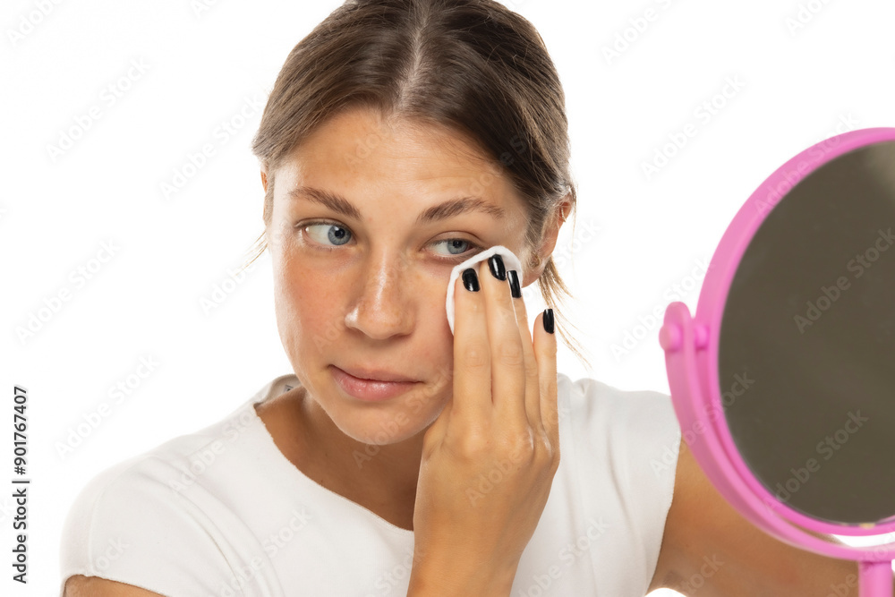 Portrait of a young woman removing her make-up on a white studio background Portrait of a young woman removing her make-up on a white studio background