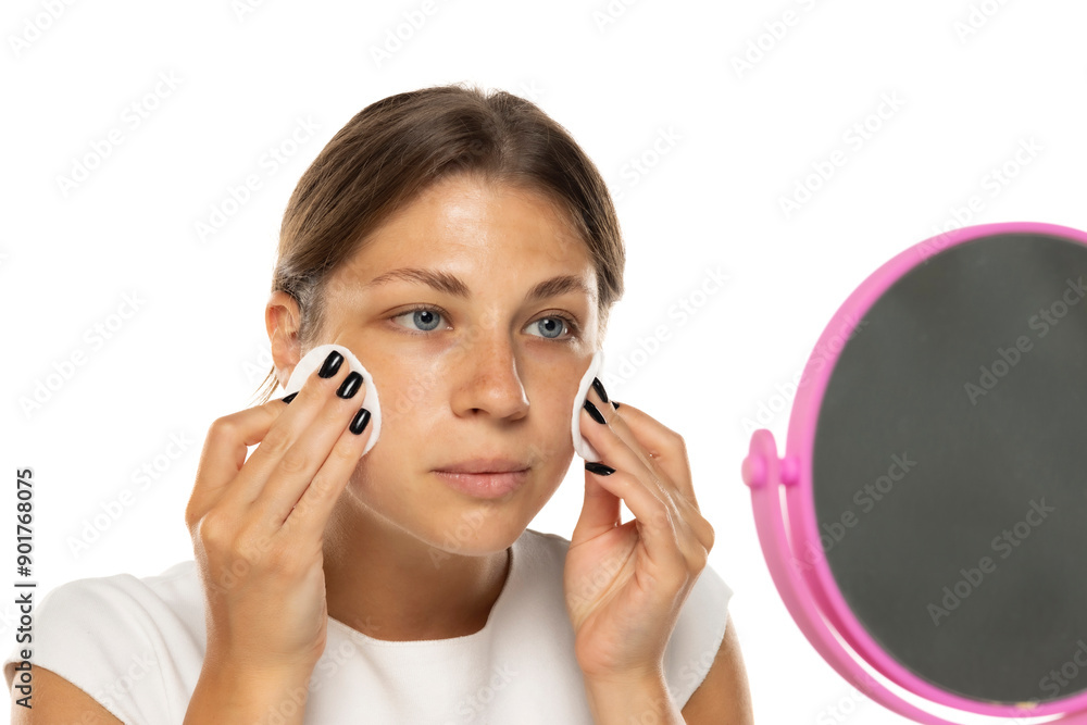 Portrait of a young woman removing her make-up on a white studio background Portrait of a young woman removing her make-up on a white studio background