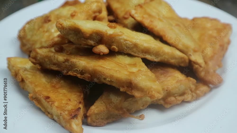 Delicious fried tempeh on white plate ready to be served, rotating display, table top view Delicious fried tempeh on white plate ready to be served, rotating display, table top view