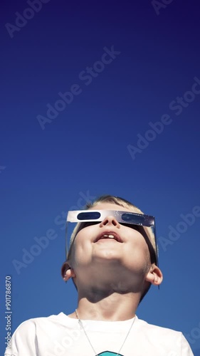 Vertical view of a young boy safely looking at a total eclipse while wearing protective glasses.  	