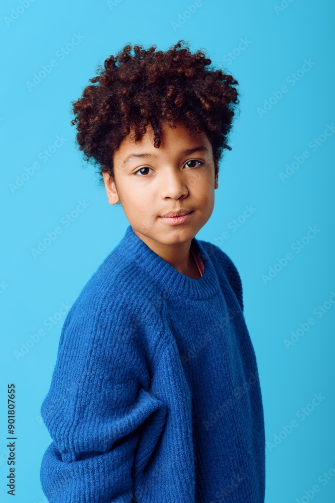 Charming portrait of a young african american boy in a blue sweater against a coordinating blue background Charming portrait of a young african american boy in a blue sweater against a coordinating blue background