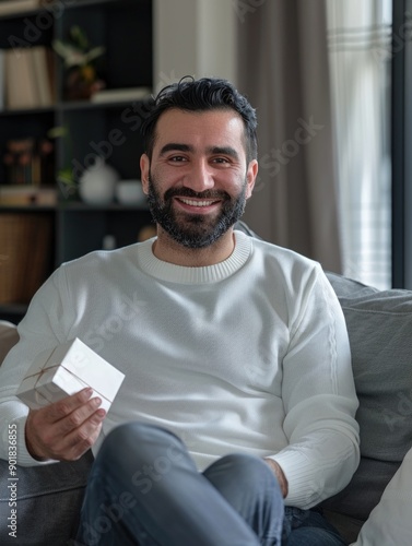 A person sitting on a couch holding a greeting card, perfect for personal use or commercial projects