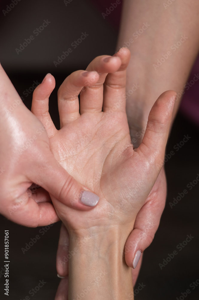 The masseuse massages the client's palms. Close-up of hands during a spa treatment. Vertical photo. The masseuse massages the client's palms. Close-up of hands during a spa treatment. Vertical photo.