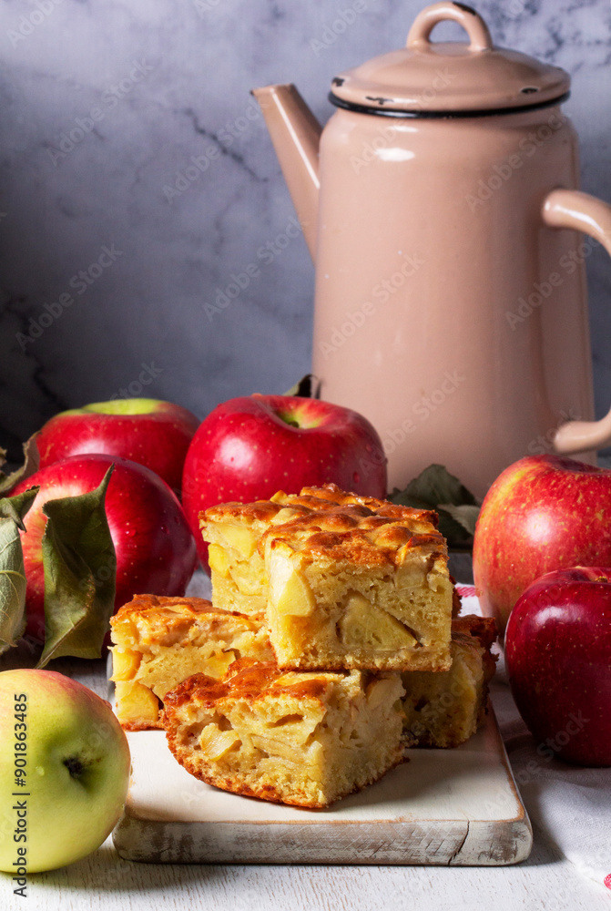 Apple pie, apples and teapot served for tea. Traditional apple dessert.