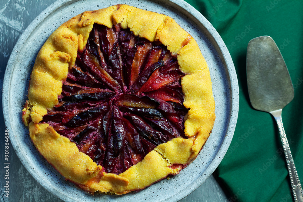 Traditional french pie galette made of corn dough with plum filling on a concrete tray.