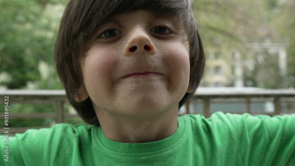 Young boy making a playful gesture and smiling outdoors, capturing the joy and innocence of childhood in a natural setting Young boy making a playful gesture and smiling outdoors, capturing the joy and innocence of childhood in a natural setting