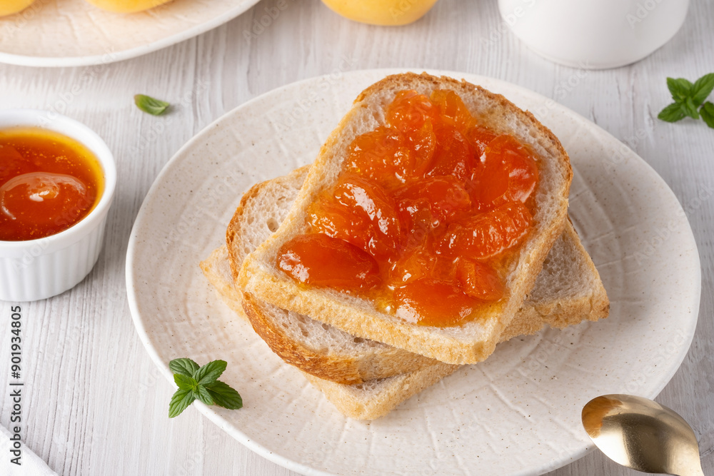 Apricot jam on bread in a white plate and a jar of apricot jam Apricot jam on bread in a white plate and a jar of apricot jam