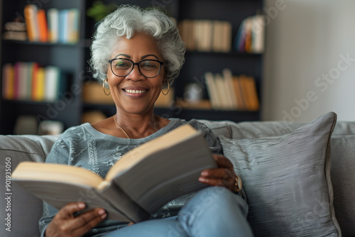 Happy senior woman enjoys reading a book on her couch in a bright living room