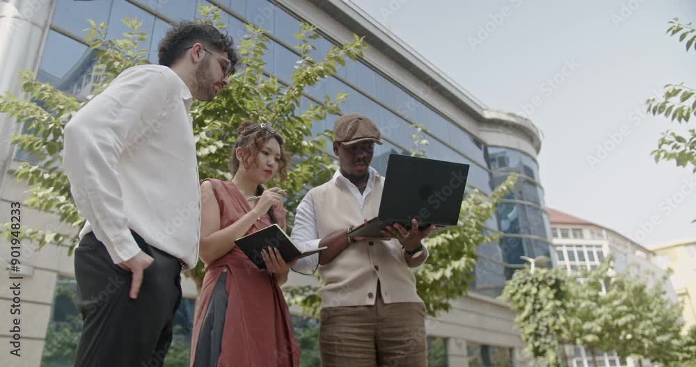 A diverse group of colleagues collaborates on a business project outdoors in a lively urban park setting, using a laptop to exchange ideas and strategies, fostering creativity and effective teamwork. A diverse group of colleagues collaborates on a business project outdoors in a lively urban park setting, using a laptop to exchange ideas and strategies, fostering creativity and effective teamwork.