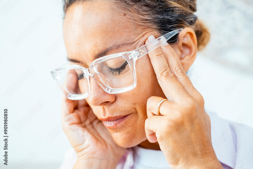 Close up portrait of upset painful mature woman touching temples for migraine head ache or stress overwork condition. Bad day and fever flu symptoms. Wearing glasses. Adult female massaging head Close up portrait of upset painful mature woman touching temples for migraine head ache or stress overwork condition. Bad day and fever flu symptoms. Wearing glasses. Adult female massaging head
