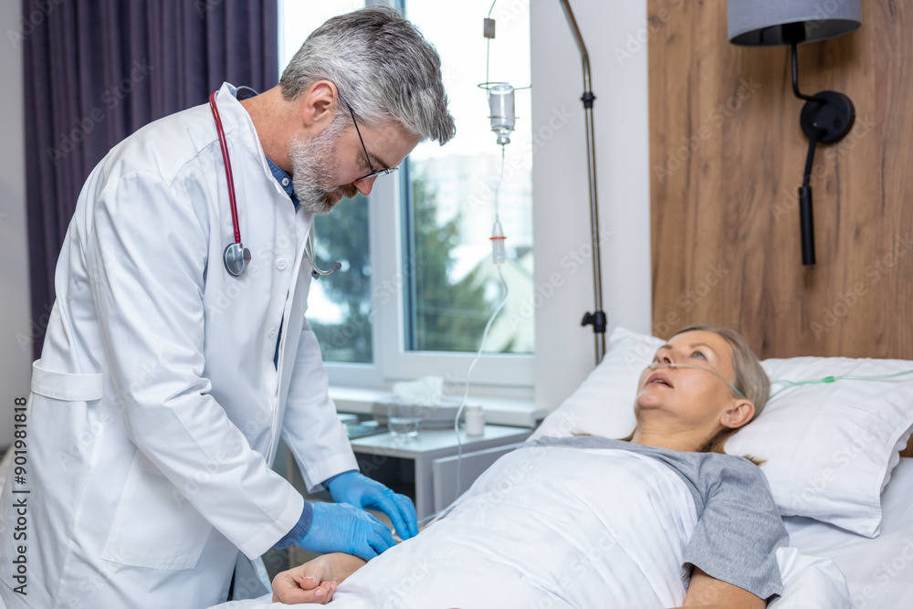 Gray-haired doctor in lab coat making IV drip to a female patient Gray-haired doctor in lab coat making IV drip to a female patient
