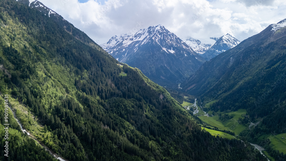 Breathtaking Aerial View of Alpine Mountains and Lush Green Valleys Under a Cloudy Sky Breathtaking Aerial View of Alpine Mountains and Lush Green Valleys Under a Cloudy Sky