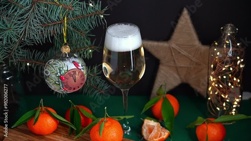 Sparkling wine effervesce in wineglass on table with mandarins fir brunch and garland. Christmas concept