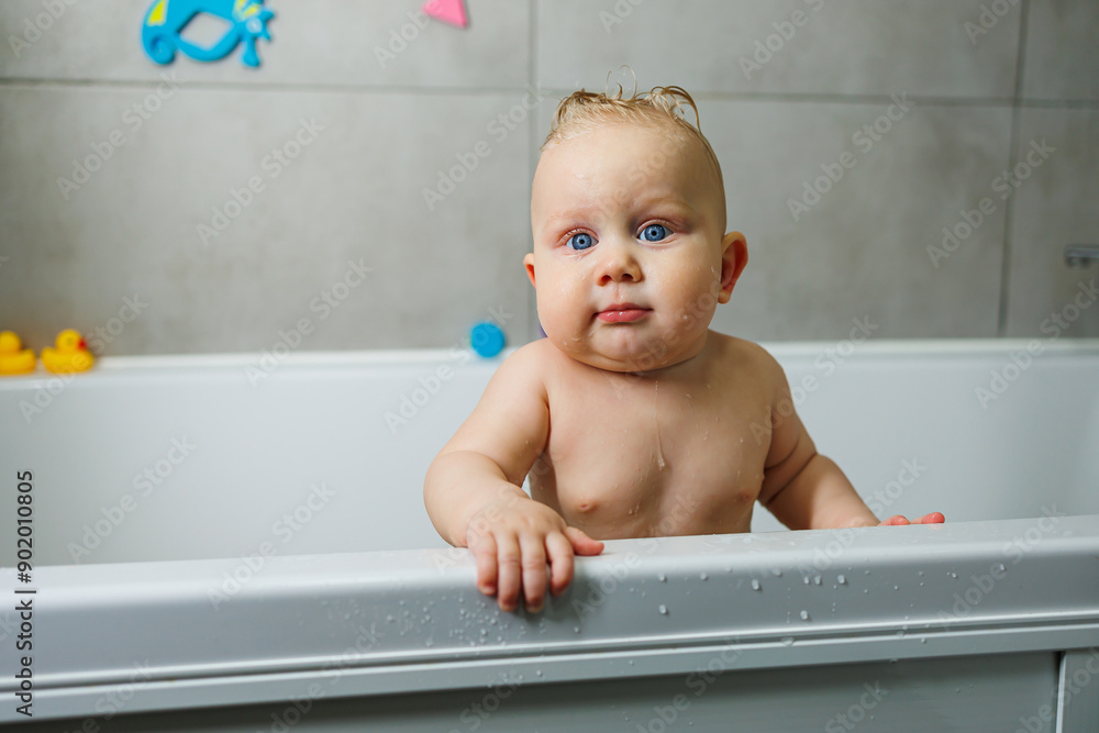 A blue-eyed baby with a bare torso is standing in the bathroom and smiling. Emotions of joy in a baby. Baby's personal hygiene. A blue-eyed baby with a bare torso is standing in the bathroom and smiling. Emotions of joy in a baby. Baby's personal hygiene.