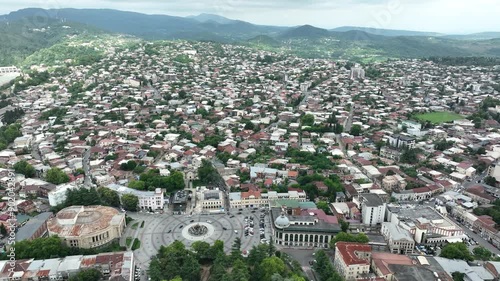 Aerial view of square with roundabout intersection with Colchis fountain in the middle of it filmed by drone in Kutaisi city. Cars are driving around it along buildings. photo