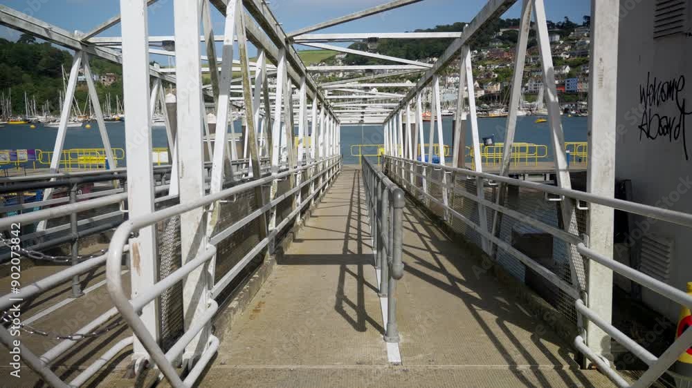 Metal pedestrian bridge leading to the boarding of tourist boats. Passage leading to public water transport on a sunny day. Metal pedestrian bridge leading to the boarding of tourist boats. Passage leading to public water transport on a sunny day.