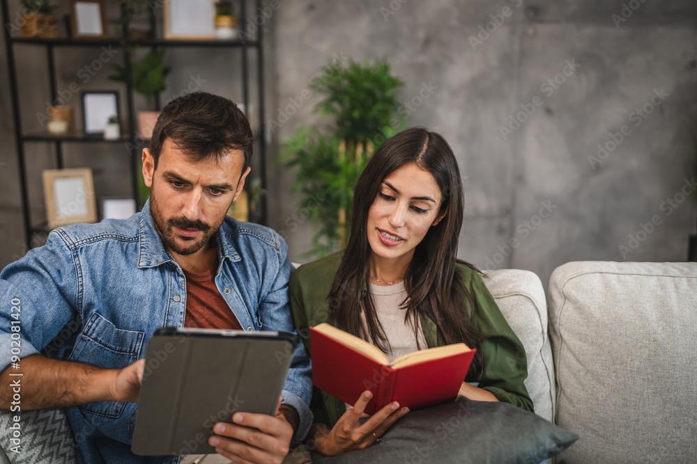 Casual couple relax with book and tablet have leisure activities Casual couple relax with book and tablet have leisure activities