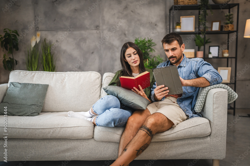 Casual couple relax with book and tablet have leisure activities Casual couple relax with book and tablet have leisure activities
