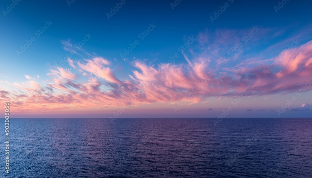 Cirrus clouds tinted pink by the sun at sunset over a calm blue ocean Cirrus clouds tinted pink by the sun at sunset over a calm blue ocean