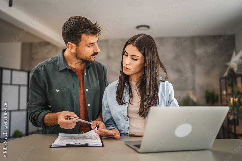 Adult couple work from home together on clipboard and laptop Adult couple work from home together on clipboard and laptop