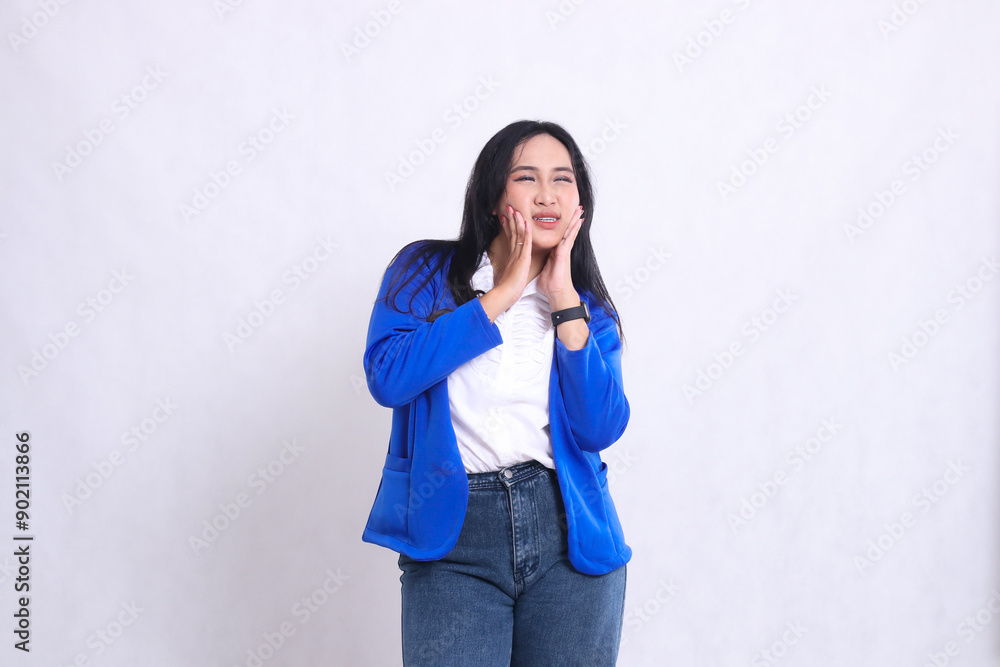 expression of beautiful young office girl wearing blue formal suit standing candid grimacing in pain toothache both hands holding cheeks. for company content, health, business, care, drinks expression of beautiful young office girl wearing blue formal suit standing candid grimacing in pain toothache both hands holding cheeks. for company content, health, business, care, drinks