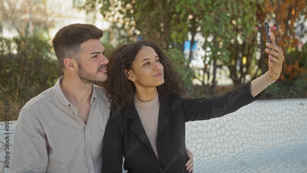 A woman and man share a moment taking a selfie together in an outdoor park setting. A woman and man share a moment taking a selfie together in an outdoor park setting.