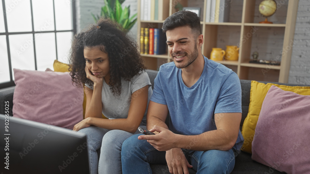 A woman and a man comfortably relax together in a modern living room, watching television and enjoying quality time.