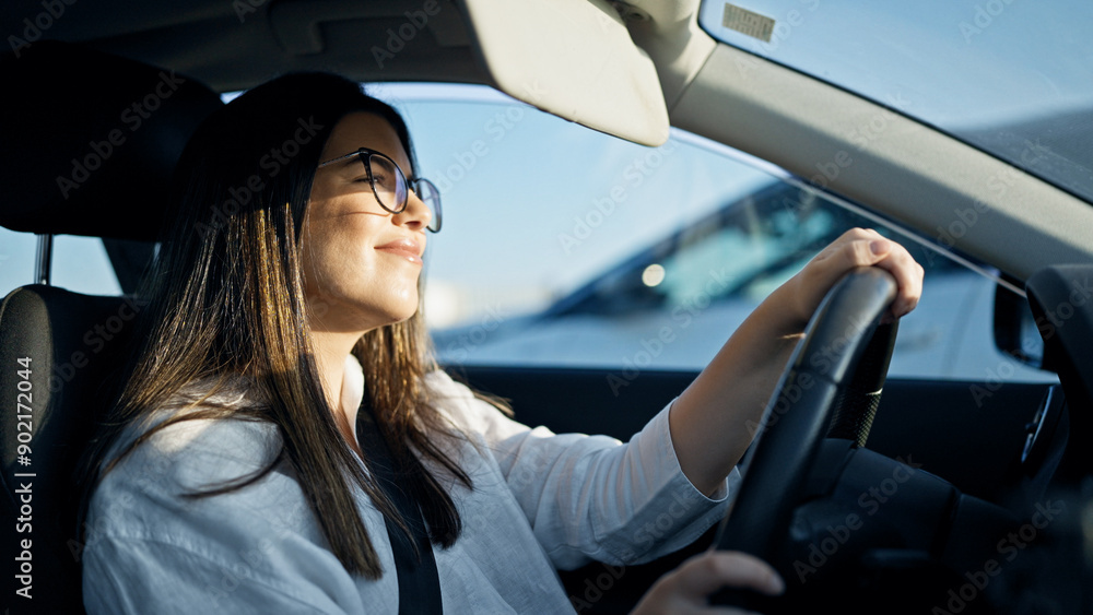 Young beautiful hispanic woman driving a car smiling wearing glasses on the road Young beautiful hispanic woman driving a car smiling wearing glasses on the road
