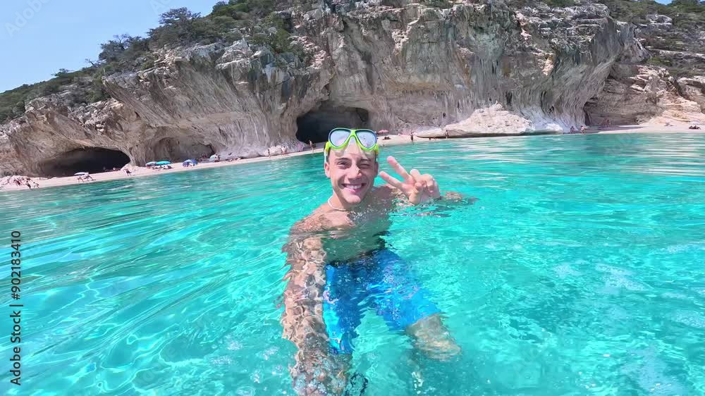 Young man holding camera taking selfie swimming in turquoise water looking camera smiling having fun. Happy cheerful male enjoying summer
Young man holding camera taking selfie swimming in turquoise water looking camera smiling having fun. Happy cheerful male enjoying summer