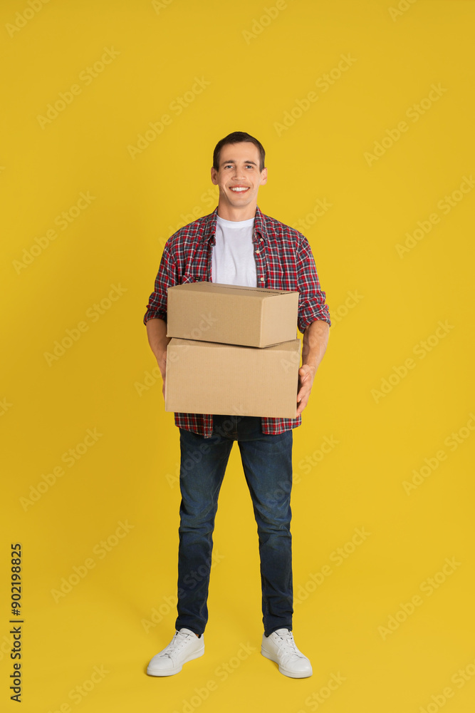 Moving into new house. Man with cardboard boxes on yellow background Moving into new house. Man with cardboard boxes on yellow background