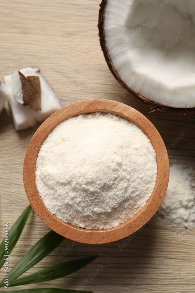 Fresh coconut flour in bowl, nut and palm leaf on wooden table, flat lay Fresh coconut flour in bowl, nut and palm leaf on wooden table, flat lay