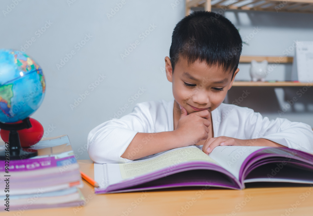 The child smile thinking sitting at table with book. Education, Childhood, People, Homework and school concept. Student learning study reading book while sitting at home. The child smile thinking sitting at table with book. Education, Childhood, People, Homework and school concept. Student learning study reading book while sitting at home.