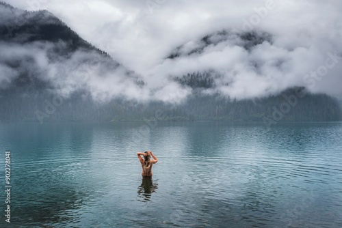 Woman swimming in the lake against mountains with clouds. Early morning. Baker Lake. Washington State. USA photo