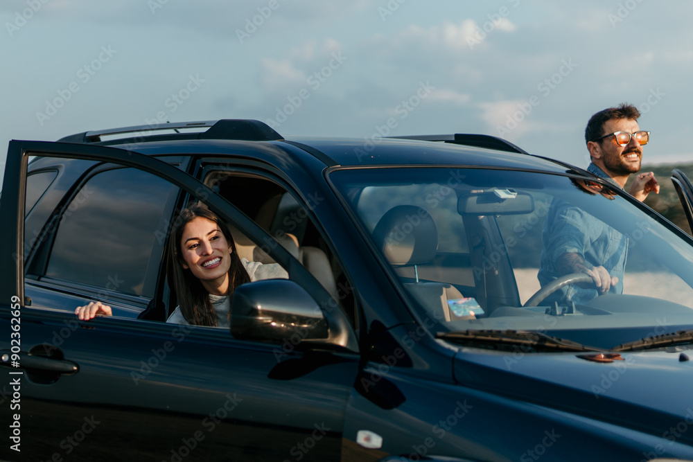 Loving urban styled couple getting out of the car, ready to enjoy sunset in the nature Loving urban styled couple getting out of the car, ready to enjoy sunset in the nature