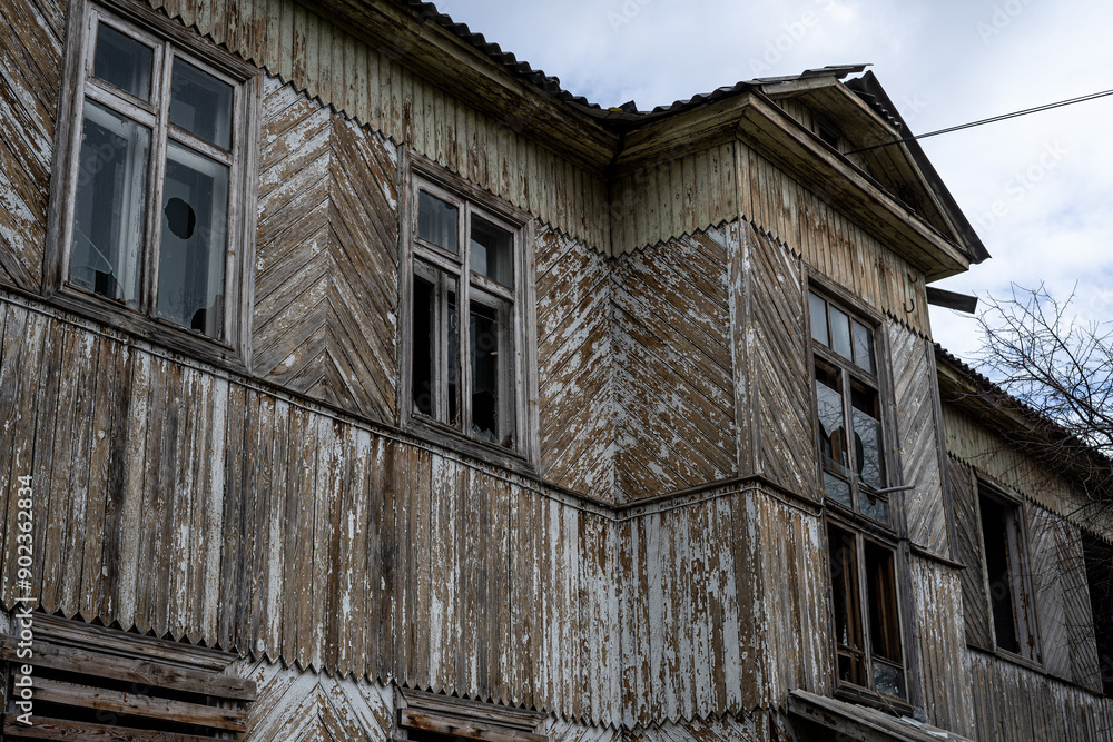 An old abandoned wooden house with damaged windows and a crumbling roof An old abandoned wooden house with damaged windows and a crumbling roof