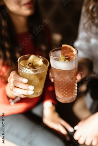 Two cute girls are drinking refreshing cocktails in a beautiful bar