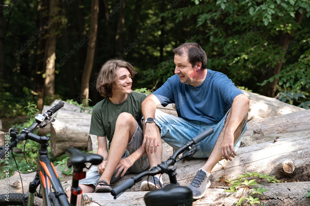 Father and teenager son have a rest in forest while bike ride outdoor, family summer activity Father and teenager son have a rest in forest while bike ride outdoor, family summer activity