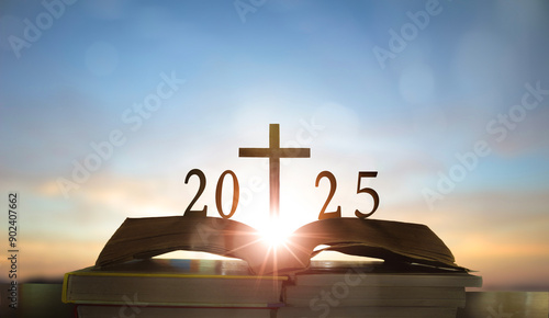 Photography Open bible with christian cross and 2025 on top over sunset sky background